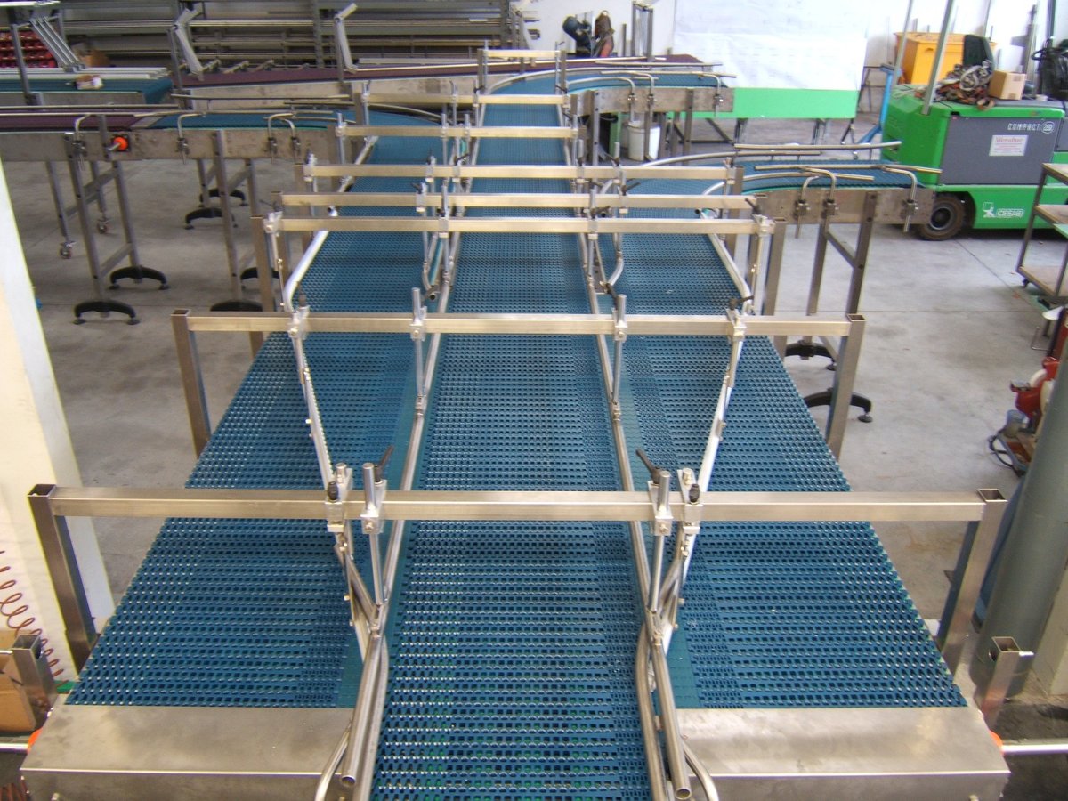 Sistema di trasporto con nastri modulari blu e struttura metallica in stabilimento